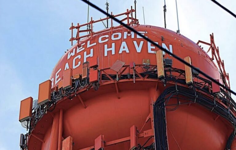 a large orange water tower with the words "WELCOME BEACH HAVEN" written in white letters on the side