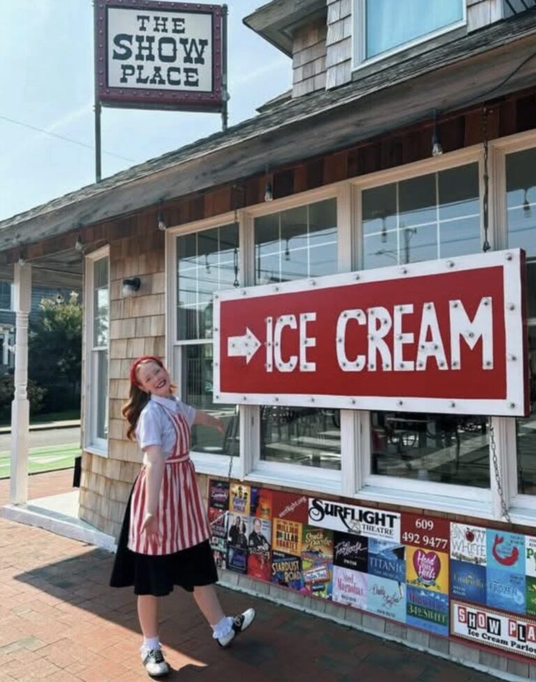 an exterior view of the show place with a smiling employee near the ice cream sign