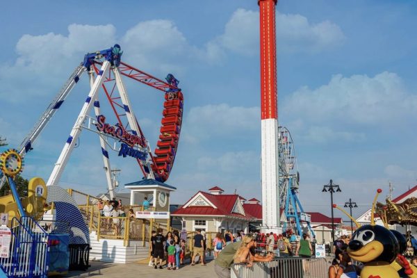 a lively amusement park with rides like "Sea Dragon's Revenge" and a tall drop tower, along with a Ferris wheel