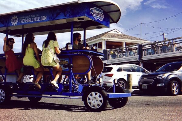 a group of people enjoying a pedal-powered cycle, with a colorful blue and wooden design