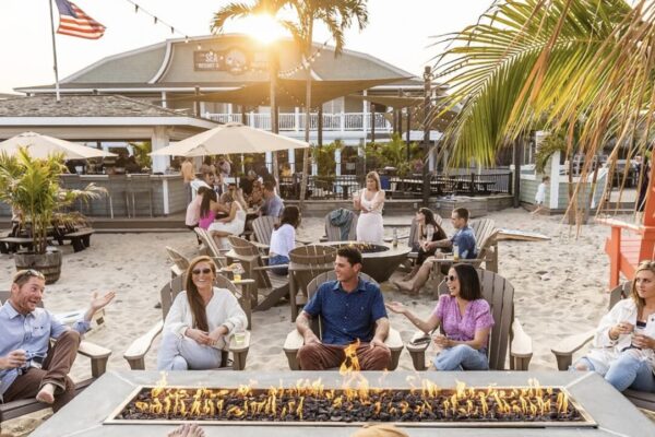 a group of people in front of a firepit and having drinks