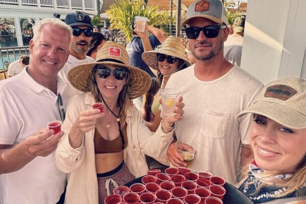 a group of people holding their martini and a server holding a bunch of drinks in a tray