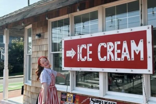 an exterior view of the show place with a smiling employee near the ice cream sign